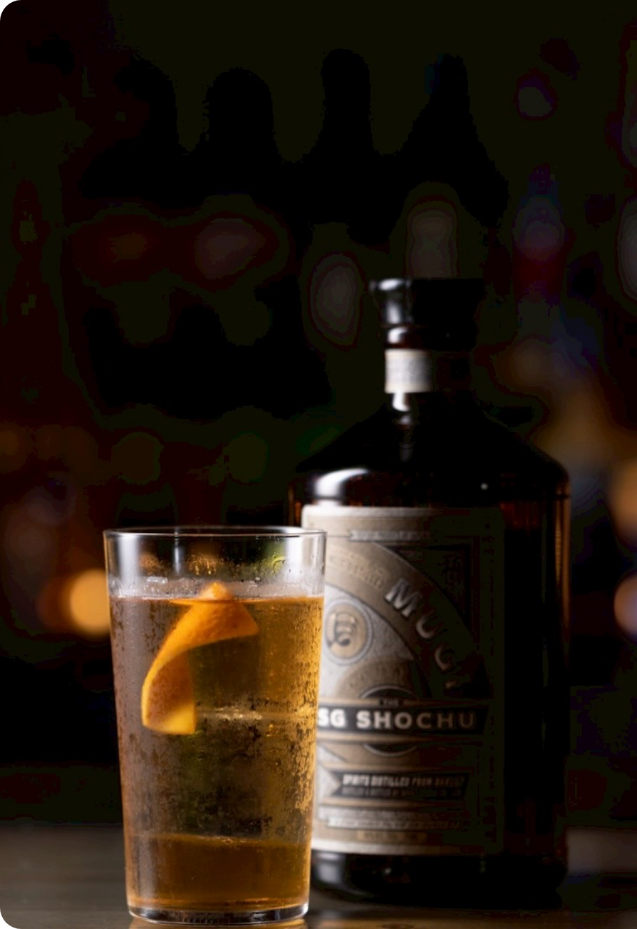 香ばしい焼酎をソーダで割り、オレンジピールを添えた上品なハイボール。落ち着いたバーの照明に映える一杯